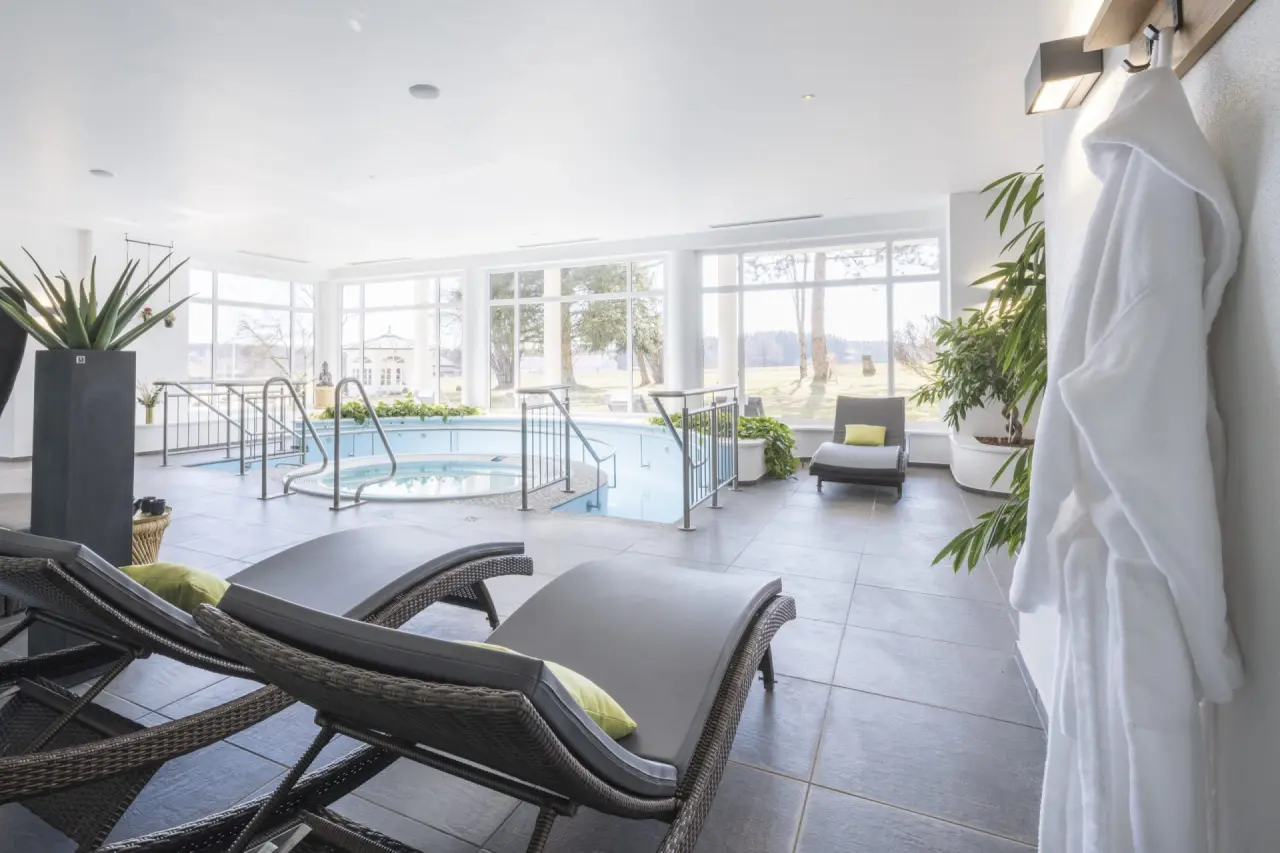 Tanneck Golf & Spa in Bad Wörishofen – Heller Innenpoolbereich mit bequemen Liegen und Bademantel | Wellnesshotel Allgäu