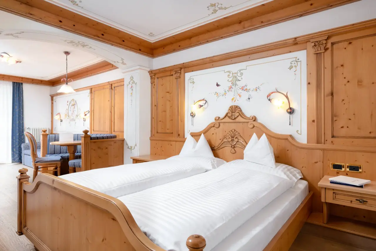 The Cacciatora Wellness & Beauty Hotel in Canazei – Traditionelles Doppelzimmer mit Holzschnitzereien | Wellnesshotel Dolomiten
