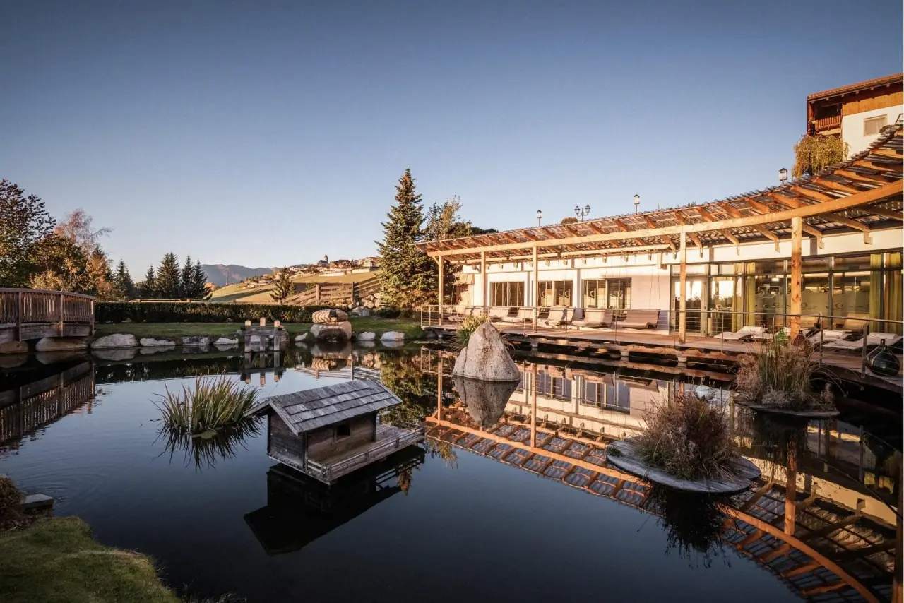 Hotel Bacherhof in Terenten – Naturteich mit Hotelgebäude und Gartenanlage | Wellnesshotel Südtirol