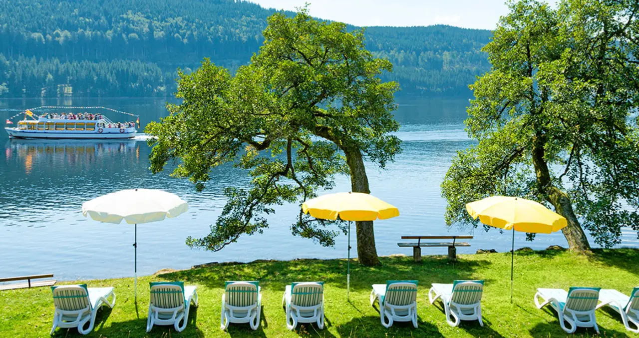 Brugger's Hotelpark am Titisee in Titisee – Liegewiese am Seeufer mit Sonnenschirmen | Wellnesshotel Schwarzwald