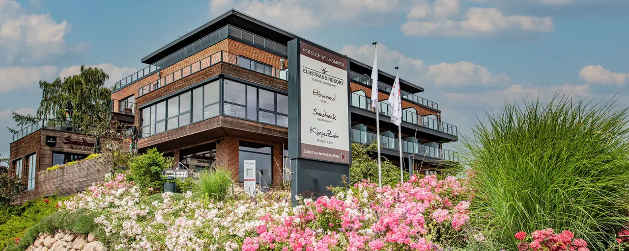 Elbstrand Resort Krautsand in Drochtersen-Krautsand – Modernes Hotelgebäude mit Blumenbeet | Wellnesshotel Nordsee