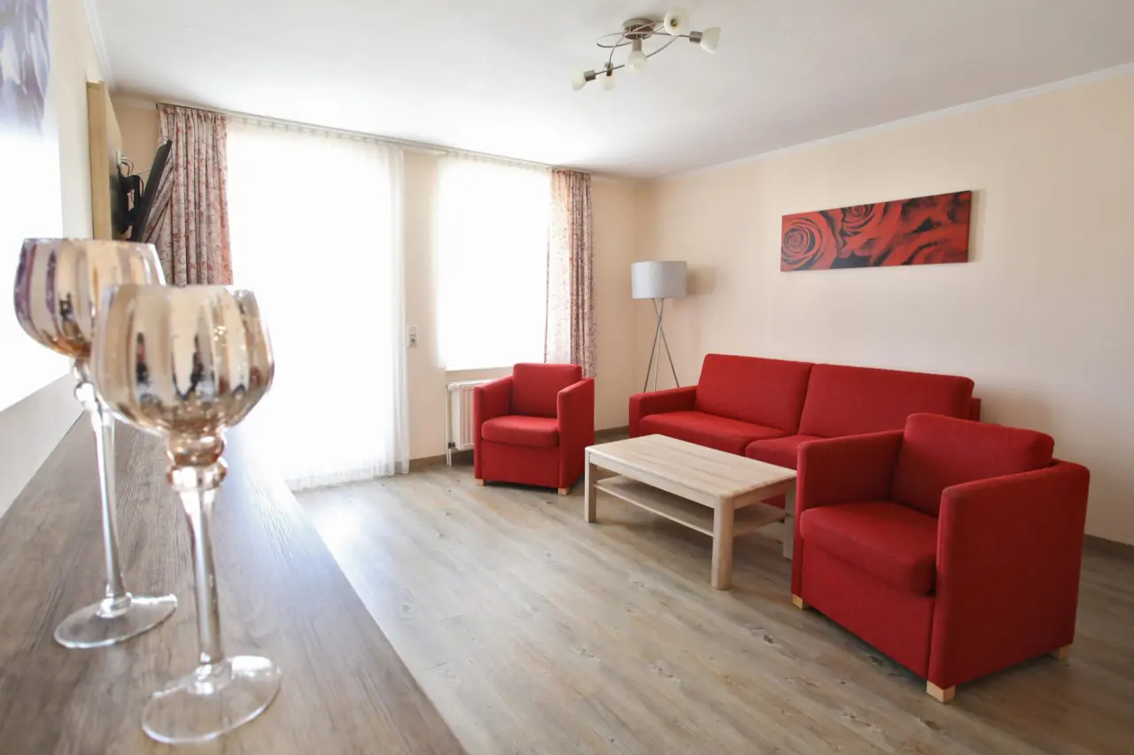 AKZENT Waldhotel SPA Rügen in Ostseebad Göhren – Komfortables Hotelzimmer mit rotem Sofa | Wellnesshotel Rügen