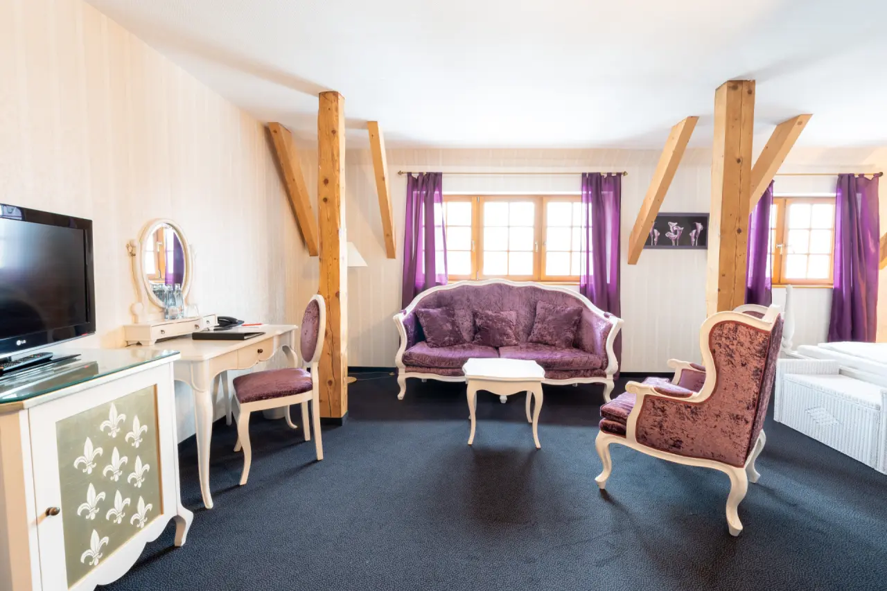 Hotel & Spa Wasserschloss Westerburg in Westerburg – Geräumige Suite mit lila Sitzmöbeln | Wellnesshotel Westerwald