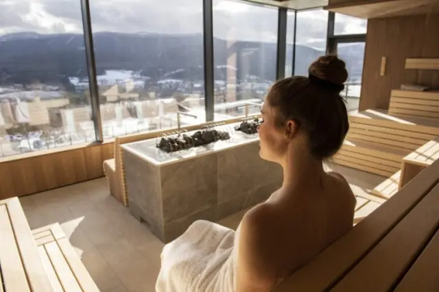 Hotel Sonnenhof in Lam – Panorama-Sauna mit Bergblick und entspannter Frau | Wellnesshotel Bayerischer Wald