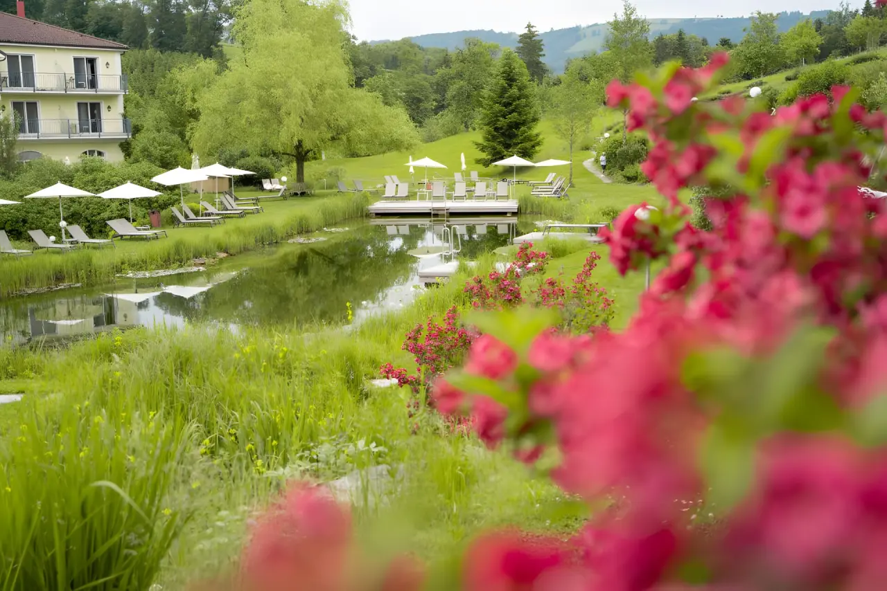 RelaxResort Kothmühle in Neuhofen an der Ybbs – Blühender Gartenbereich mit Blick auf den Naturbadeteich | Wellnesshotel Mostviertel