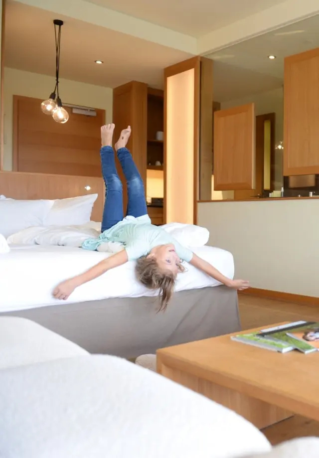 Ulrichshof Baby & Kinder Bio-Resort in Rimbach – Mädchen spielt vergnügt auf dem Bett im Familienzimmer | Wellnesshotel Bayerischer Wald