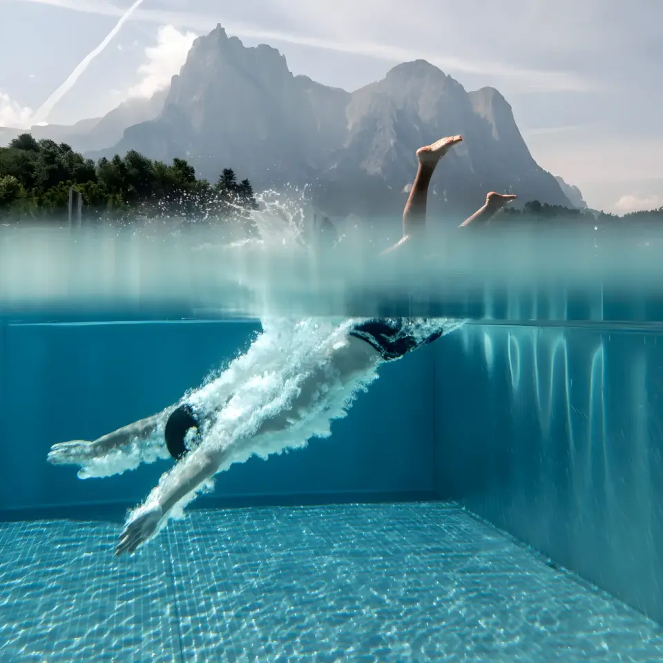 Hotel Alpenflora in Kastelruth – Schwimmer taucht in den Pool mit Dolomitenpanorama | Wellnesshotel Südtirol