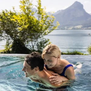 Hotel Seevilla Wolfgangsee in St. Wolfgang – Glückliches Paar im Infinity-Pool mit Seeblick | Wellnesshotel Salzkammergut
