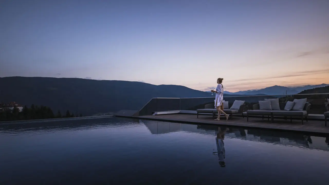 Terentnerhof in Terenten – Infinity-Pool mit Frau und Alpenpanorama bei Sonnenuntergang | Wellnesshotel Südtirol