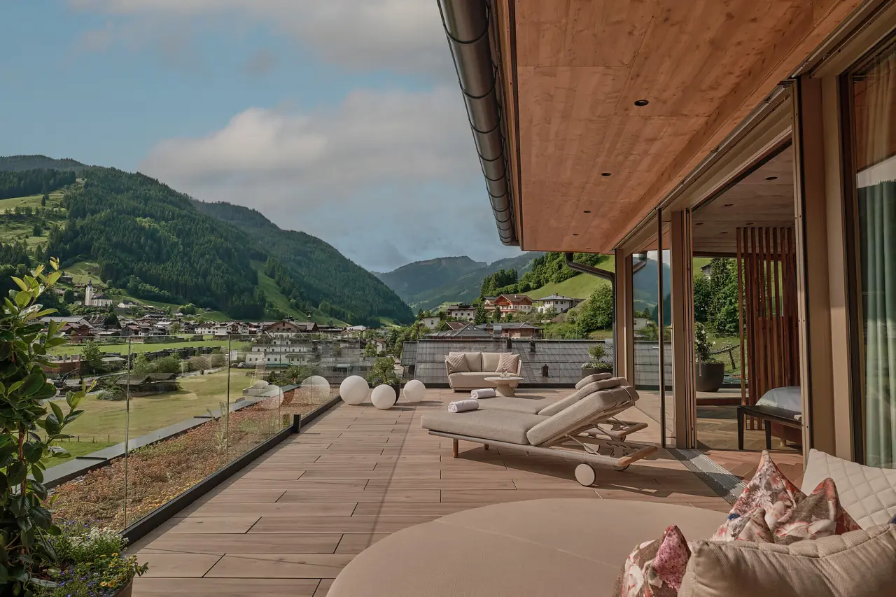 DAS EDELWEISS Salzburg Mountain Resort in Großarl – Sonnenterrasse mit Bergblick und Liegen | Wellnesshotel Salzburger Land