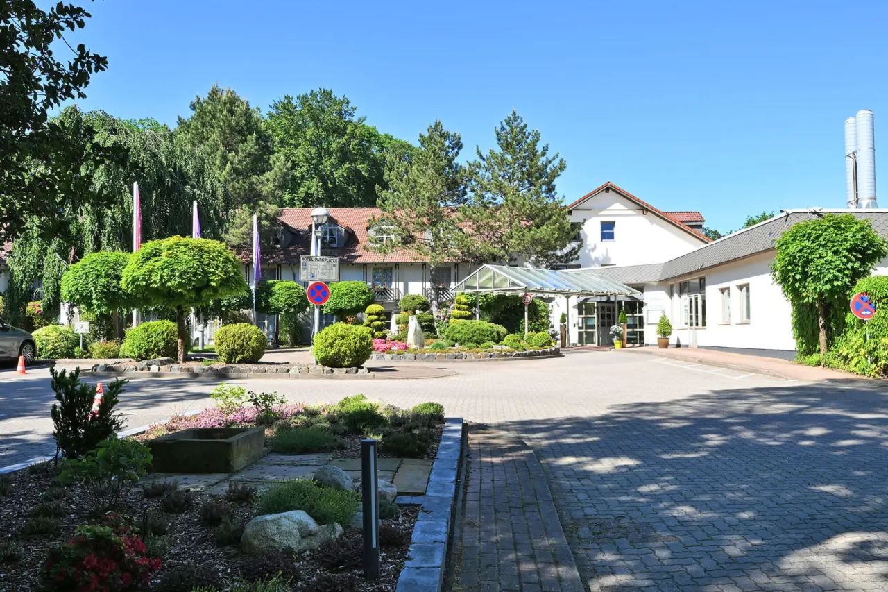 Landhotel Schnuck in Schneverdingen – Außenansicht des Hoteleingangs mit Garten | Wellnesshotel Lüneburger Heide