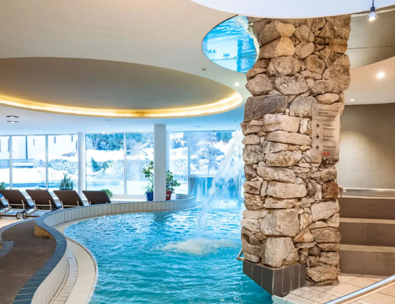 Feldmilla Design Hotel in Sand in Taufers – Innenpool mit Wasserfall und Blick auf die Winterlandschaft | Wellnesshotel Südtirol