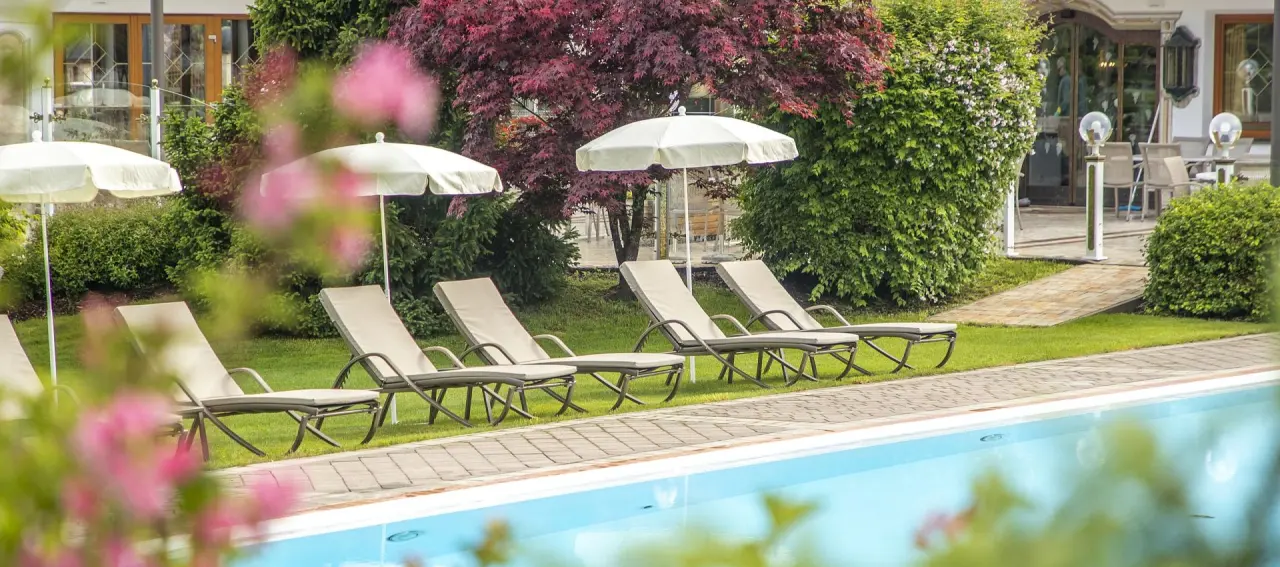 Hotel Der Lärchenhof in Erpfendorf – Außenpool mit Liegen und grüner Gartenanlage | Wellnesshotel Tirol