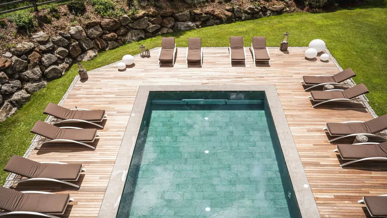 Falkensteiner Hotel Antholz in St. Martin in Gsies – Außenpool mit Holzterrasse und Liegen | Wellnesshotel Südtirol
