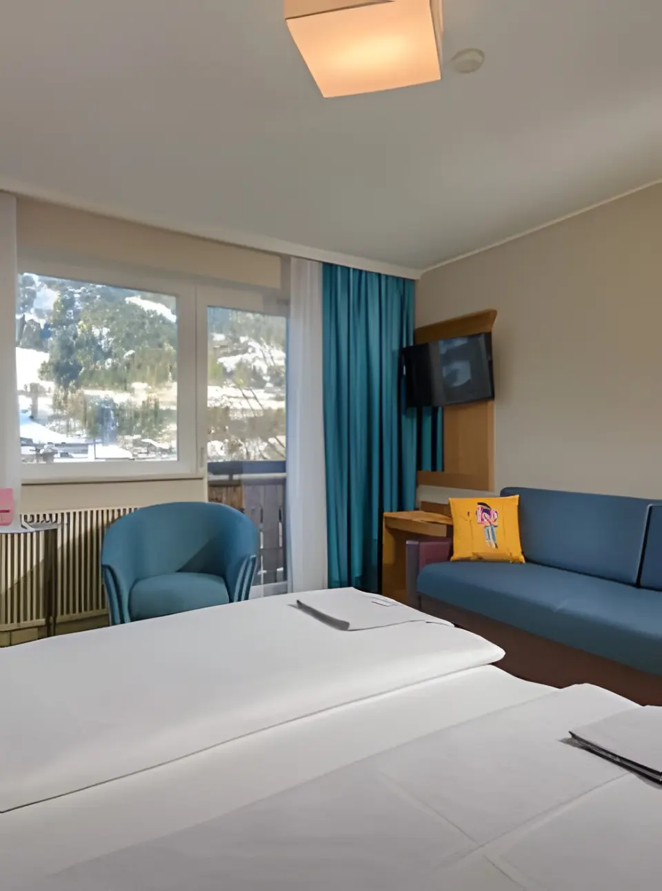 Hotel Blü Gastein in Bad Hofgastein – Gemütliches Zimmer mit Sofa und Blick auf die verschneiten Berge | Wellnesshotel Gastein
