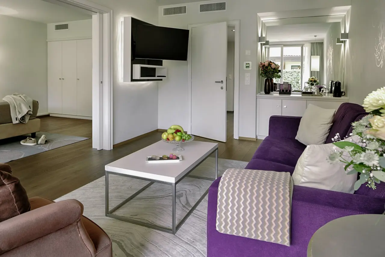 Giardino Ascona in Ascona – Gemütlicher Wohnbereich einer Suite mit Sofa und TV | Wellnesshotel Tessin