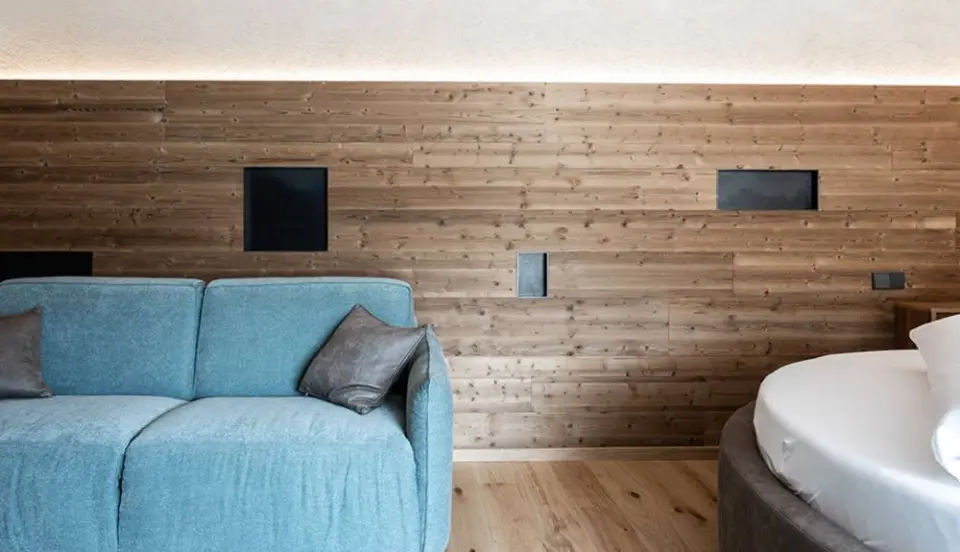 Hotel Traube Post am Reschensee in Reschen – Modernes Hotelzimmer mit Sofa und Holzwand | Wellnesshotel Vinschgau