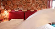 Beauty & Vital Hotel Maria in Cavalese – Schlafzimmer mit Holzwand und rotem Kopfteil | Wellnesshotel Trentino