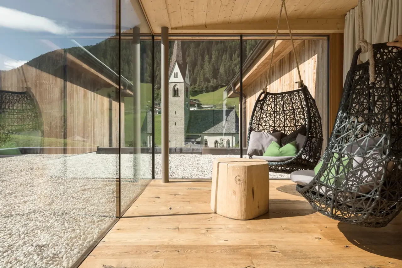 Naturhotel Rainer in Ratschings – Entspannungsbereich mit Hängesesseln und Kirchenblick | Wellnesshotel Südtirol