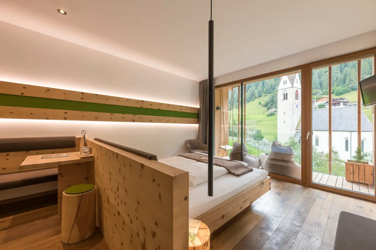 Naturhotel Rainer in Ratschings – Modernes Zimmer mit Panoramablick auf Kirche und Berge | Wellnesshotel Südtirol