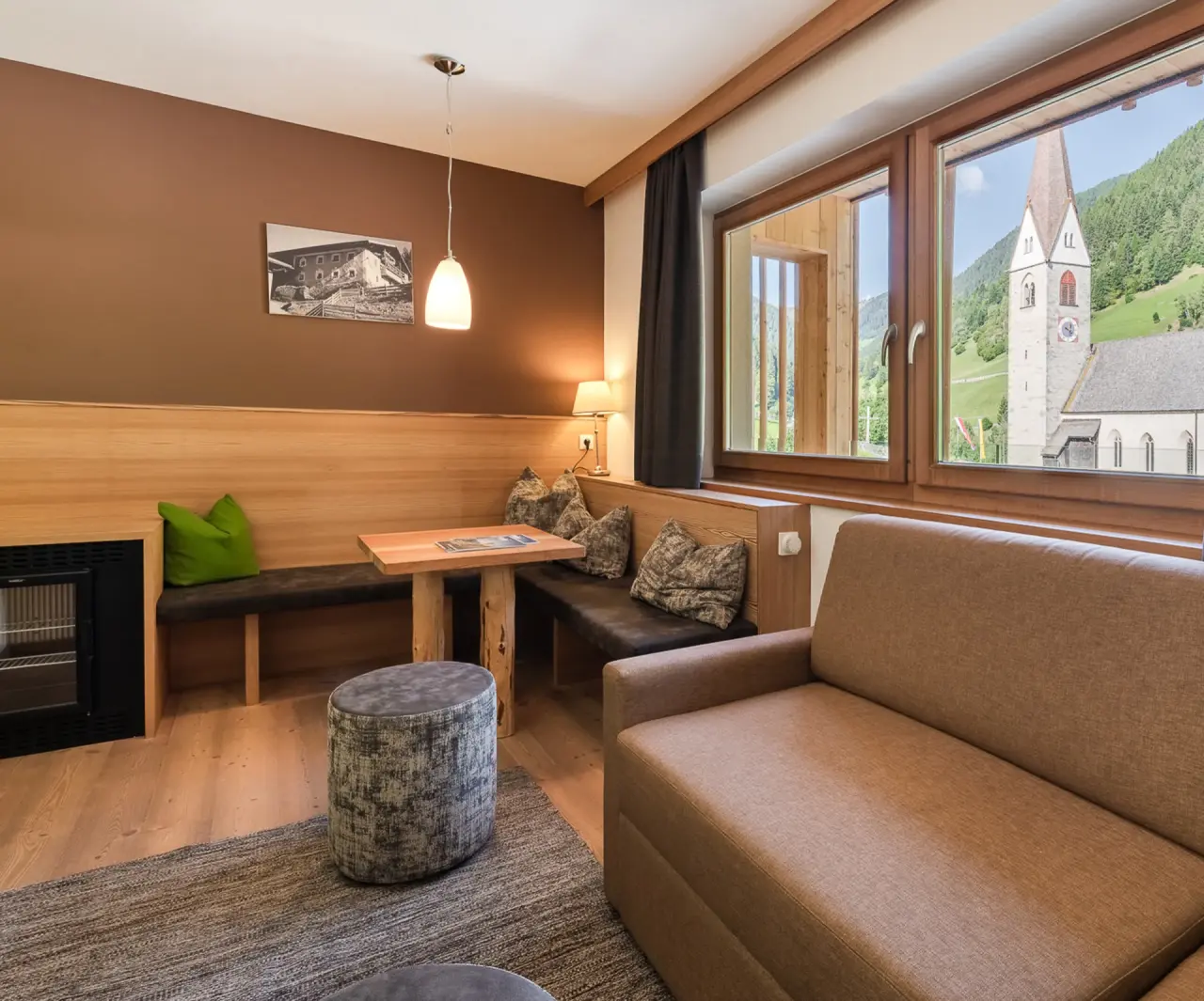 Naturhotel Rainer in Ratschings – Wohnbereich einer Suite mit Sitzgruppe und Kirchenblick | Wellnesshotel Südtirol