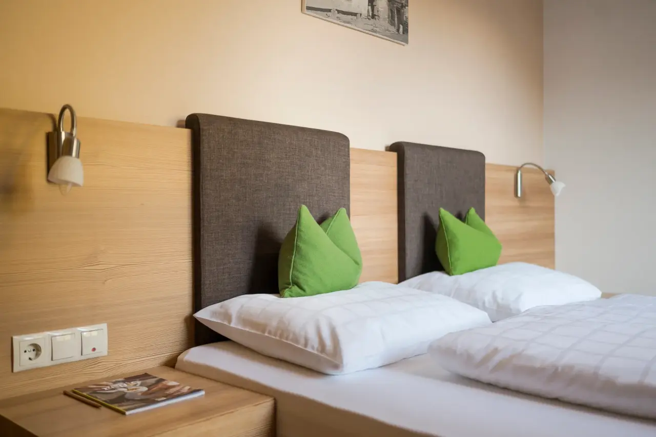 Naturhotel Rainer in Ratschings – Gemütliches Bett mit grünen Kissen im Hotelzimmer | Wellnesshotel Südtirol