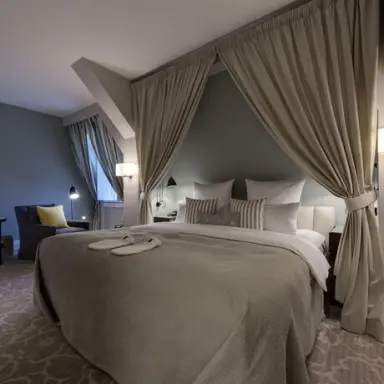 WEISSENHAUS Private Nature Luxury Resort in Hohwacht – Komfortables Schlafzimmer mit Vorhängen und Hausschuhen | Wellnesshotel Ostsee