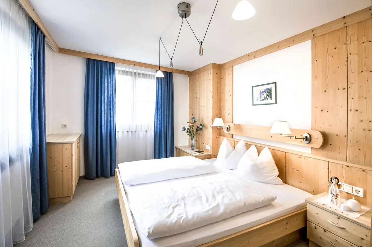Residence Montana in Kastelruth – Komfortables Schlafzimmer mit Doppelbett und Holzmöbeln | Wellnesshotel Südtirol
