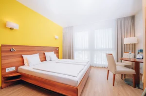 Hotel Victory Therme Erding in München – Helles Doppelzimmer mit gelber Akzentwand | Wellnesshotel Bayern