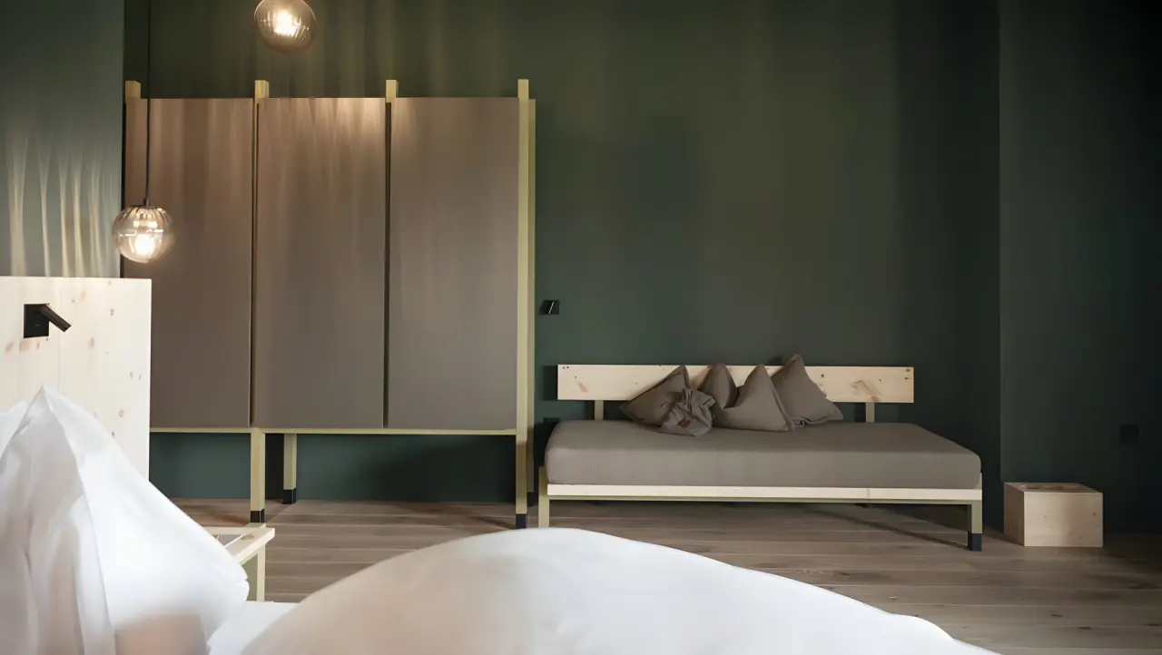 Green Luxury Hotel Pfösl in Welschnofen – Detailansicht eines Zimmers mit Schrank und Tagesbett | Wellnesshotel Südtirol