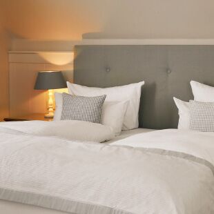Fuchsbau Romantik Hotel in Timmendorfer Strand – Detailansicht des Bettes mit grauen Kissen | Wellnesshotel Ostsee
