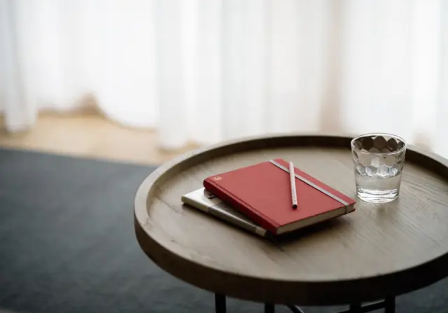 Hotel Schwarzschmied in Marling – Notizbuch und Wasserglas auf einem Holztisch | Wellnesshotel Südtirol