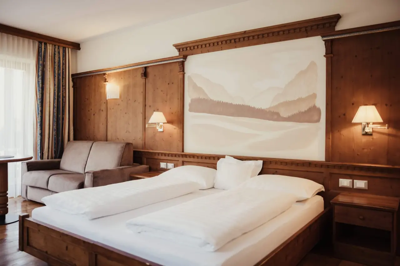 Hotel Corona in San Vigilio di Marebbe – Gemütliches Doppelzimmer mit Wandgemälde und Sofa | Wellnesshotel Dolomiten
