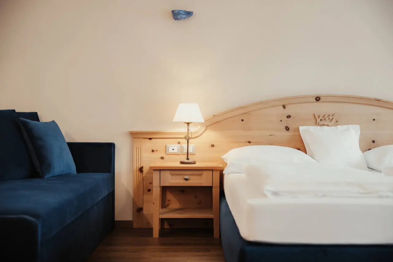 Hotel Corona in San Vigilio di Marebbe – Nachttisch und Bett in einem gemütlichen Hotelzimmer | Wellnesshotel Dolomiten