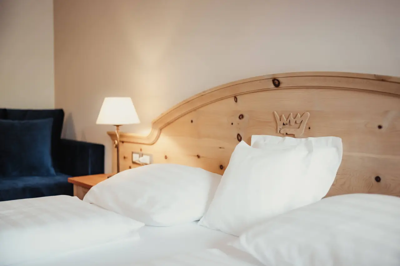Hotel Corona in San Vigilio di Marebbe – Gemütliches Doppelbett mit Holzkopfteil | Wellnesshotel Dolomiten