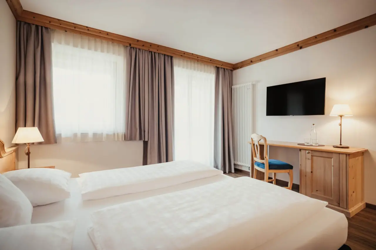 Hotel Corona in San Vigilio di Marebbe – Helles Hotelzimmer mit Doppelbett und Schreibtisch | Wellnesshotel Dolomiten