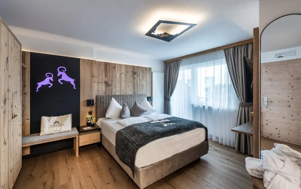 Abinea Dolomiti Romantic SPA Hotel in Kastelruth – Modernes Doppelzimmer mit Holzwand und Bademänteln | Wellnesshotel Südtirol
