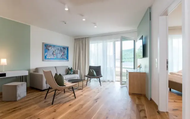 Hotel & Spa Sonne in St. Kanzian – Heller Wohnbereich mit Sofa und Blick auf den See | Wellnesshotel Kärnten