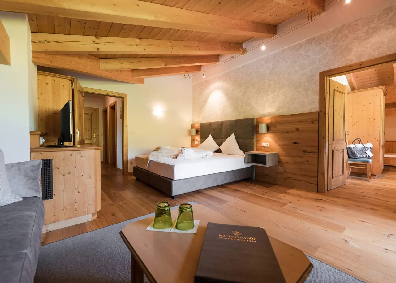 Hotel Magdalenahof in St. Martin in Gsies – Geräumiges Hotelzimmer mit Holzbalken und Sitzbereich | Wellnesshotel Gsiesertal