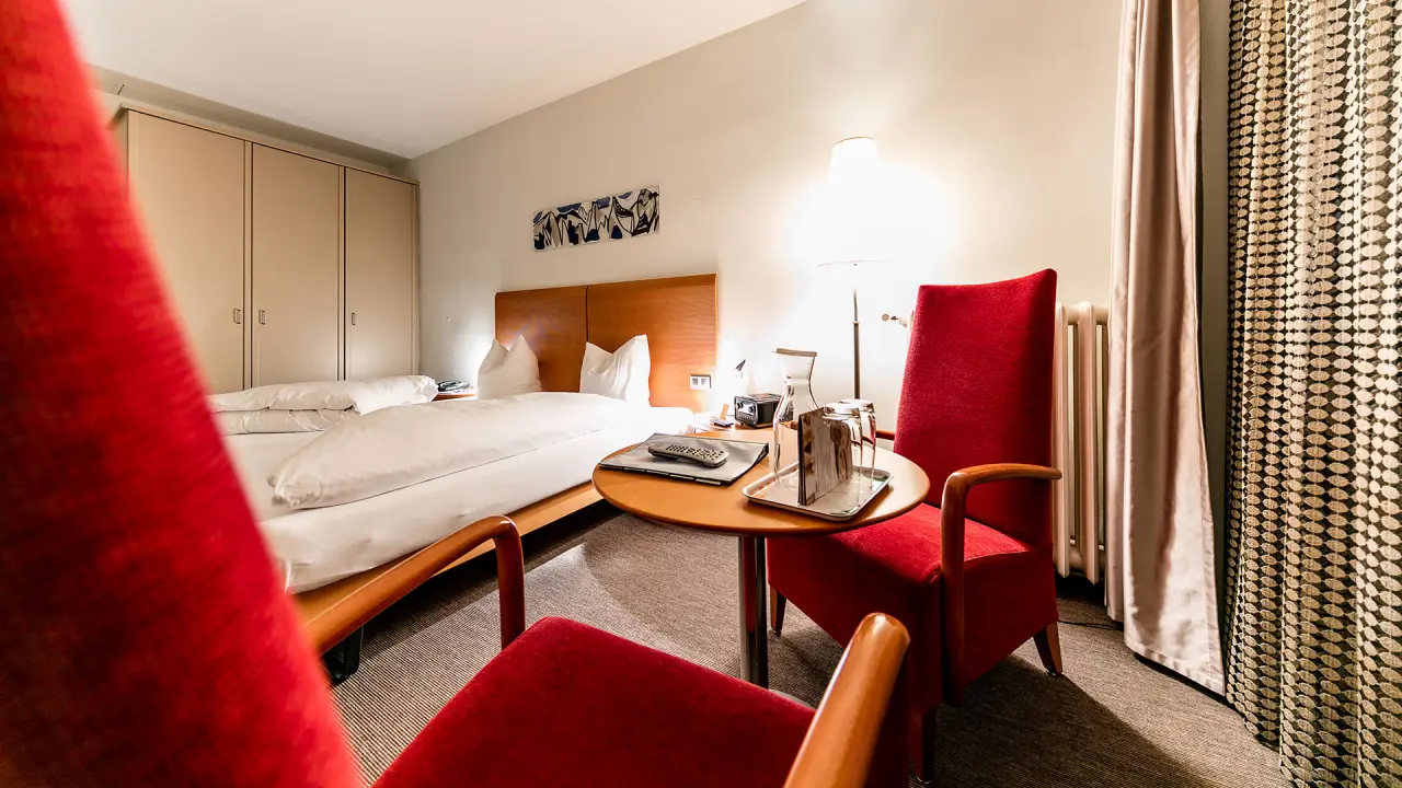 Hotel Belvédère in Scuol – Gemütliches Hotelzimmer mit roter Bestuhlung | Wellnesshotel Engadin