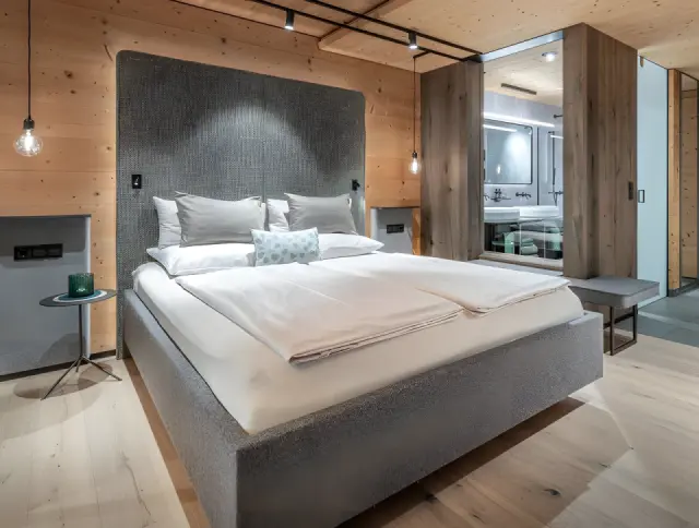 Naturhotel Waldklause in Längenfeld – Modernes Schlafzimmer mit Holzelementen und Badzugang | Wellnesshotel Ötztal