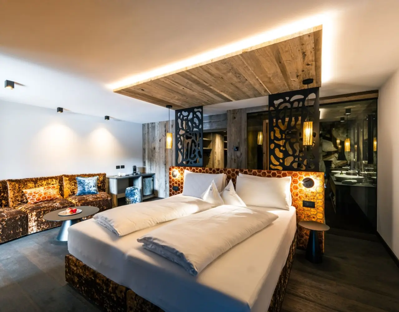Hotel Christiania in La Villa – Komfortables Doppelzimmer mit Sofa und Minibar in warmen Farbtönen | Wellnesshotel Dolomiten