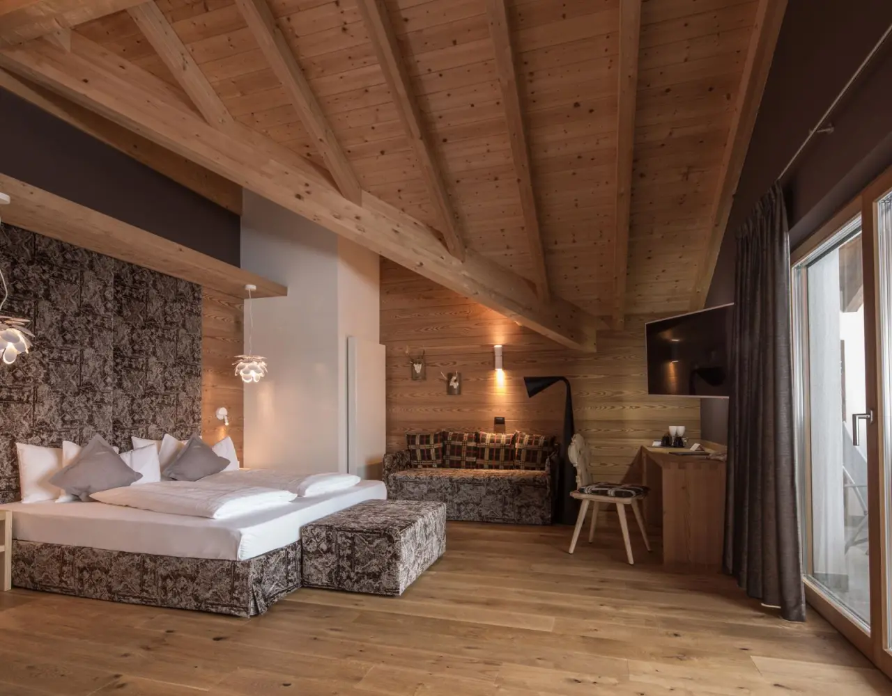 Hotel Christiania in La Villa – Geräumiges Hotelzimmer mit Holzbalken und Sitzbereich | Wellnesshotel Dolomiten