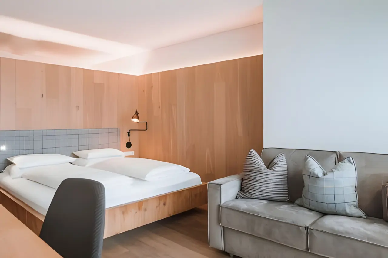 Hotel Lanerhof in Ehrenburg (Kiens) – Modernes Doppelzimmer mit Sofa und Holzwand | Wellnesshotel Südtirol