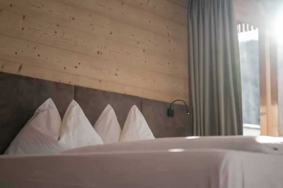 Alpine Nature Hotel Stoll in Toblach – Gemütliches Schlafzimmer mit Holzwand | Wellnesshotel Dolomiten