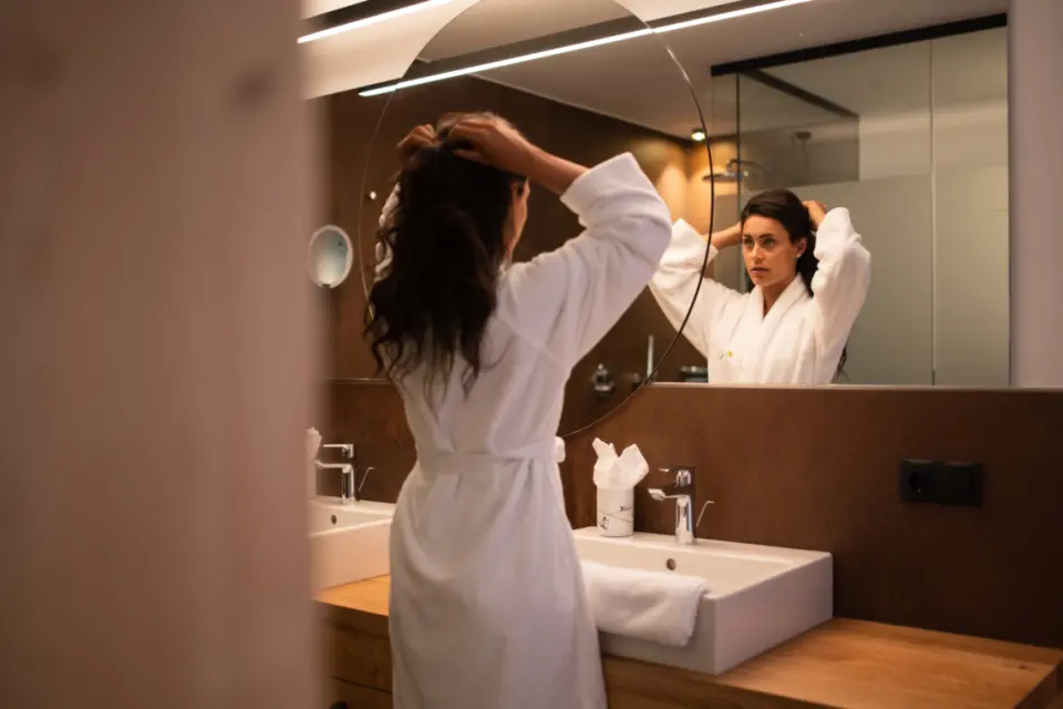 Alpine Nature Hotel Stoll in Toblach – Frau im Bademantel im modernen Badezimmer | Wellnesshotel Dolomiten