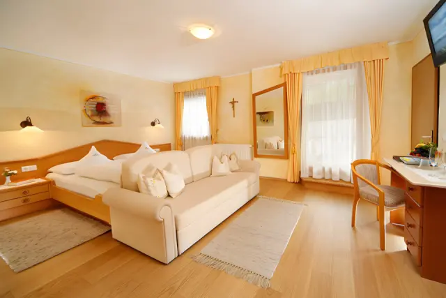 Adults Only Sonnenhotel Adler in Kastelruth – Helles Hotelzimmer mit Sofa und Holzboden | Wellnesshotel Südtirol