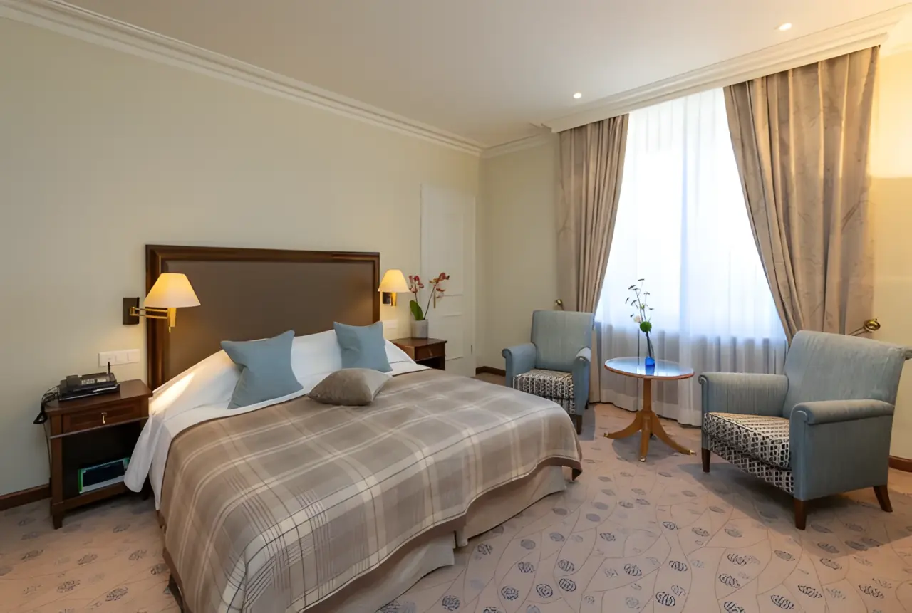 Suvretta House in St. Moritz – Gemütliches Schlafzimmer mit Doppelbett und Sitzgelegenheit | Wellnesshotel Engadin