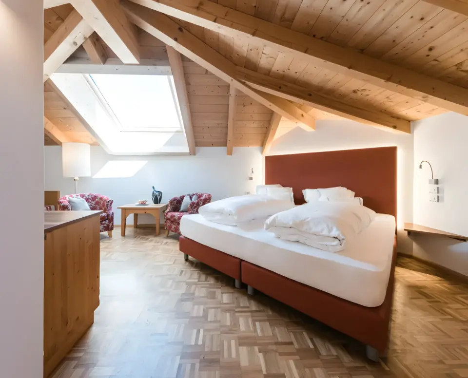 Hotel Alpenflora in Kastelruth – Gemütliches Dachzimmer mit Holzbalken und Doppelbett | Wellnesshotel Südtirol