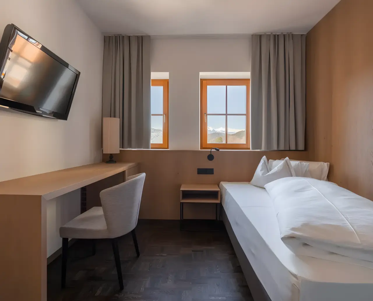 Hotel Alpenflora in Kastelruth – Einzelzimmer mit Schreibtisch und Bergblick aus dem Fenster | Wellnesshotel Südtirol